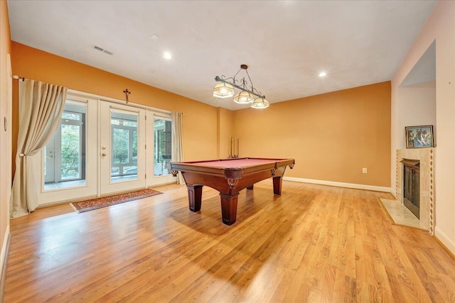 playroom featuring a tiled fireplace, pool table, and light hardwood / wood-style floors