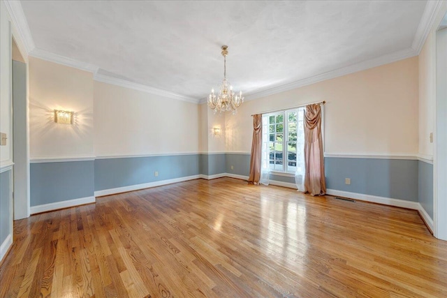 spare room with crown molding, a chandelier, and light wood-type flooring