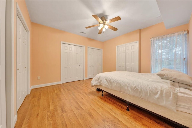 bedroom with ceiling fan, two closets, and light wood-type flooring