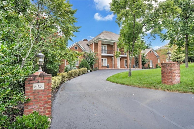 view of front of home with a balcony and a front lawn