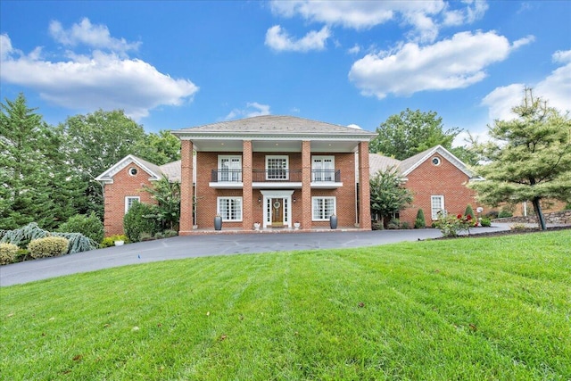 view of front of home with a balcony and a front lawn