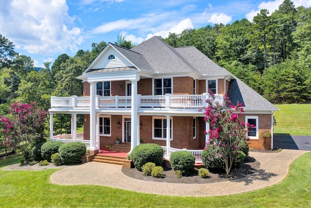 greek revival house with a front lawn, covered porch, and a balcony