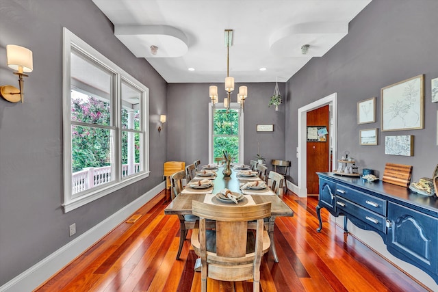 dining area with dark wood-type flooring and an inviting chandelier