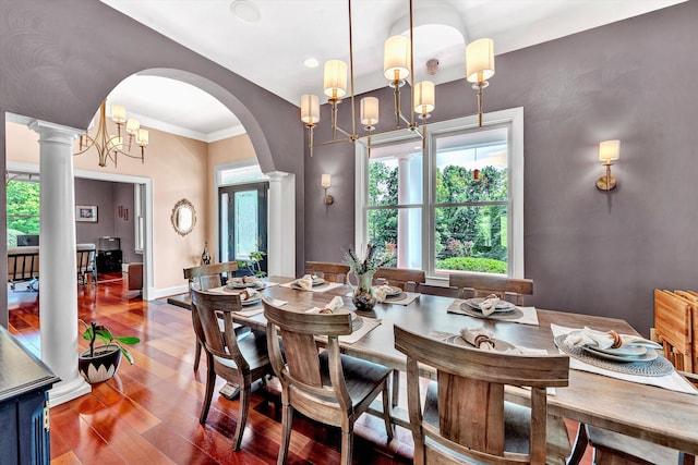 dining room with a chandelier, a healthy amount of sunlight, ornate columns, and hardwood / wood-style floors