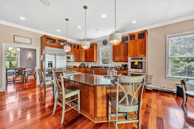 kitchen featuring a kitchen breakfast bar, an island with sink, dark wood-type flooring, and pendant lighting