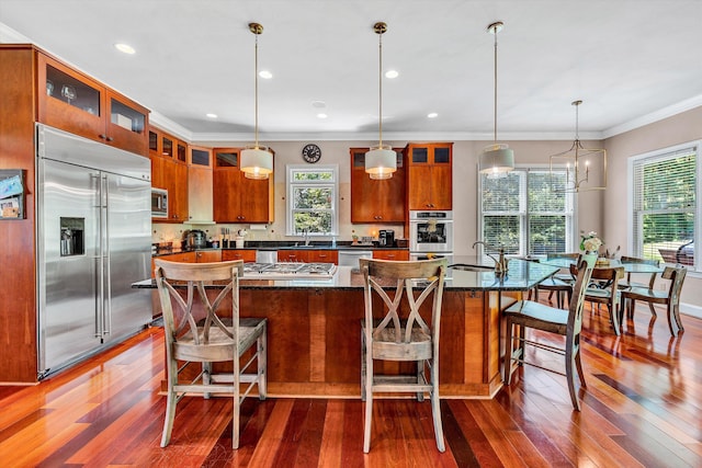 kitchen featuring dark hardwood / wood-style flooring, a kitchen breakfast bar, a center island, and built in appliances