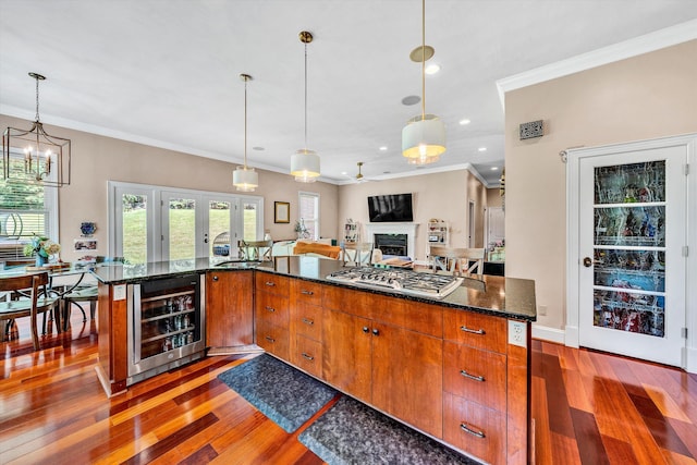 kitchen with wood-type flooring, beverage cooler, stainless steel gas stovetop, and ornamental molding