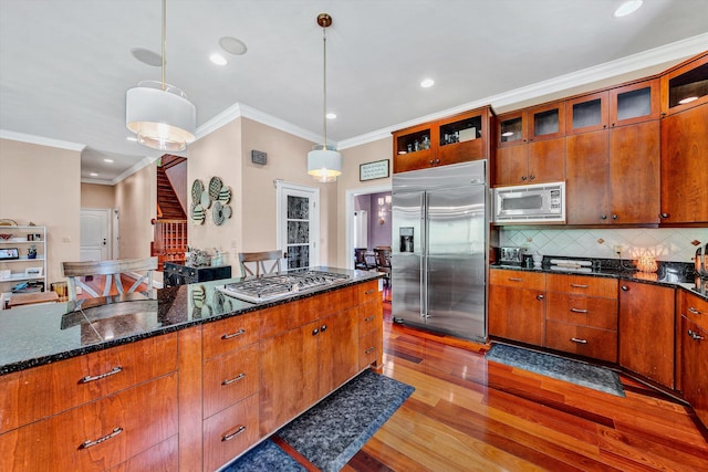 kitchen with decorative backsplash, hardwood / wood-style flooring, crown molding, and built in appliances