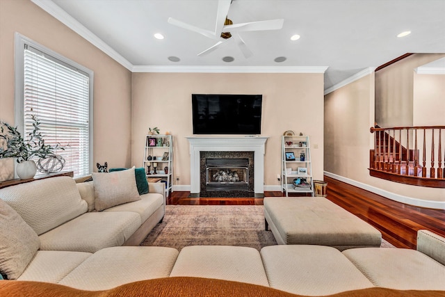 living room featuring ceiling fan, dark hardwood / wood-style flooring, ornamental molding, and a premium fireplace