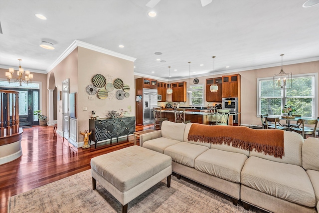 living room featuring hardwood / wood-style floors, crown molding, and a notable chandelier