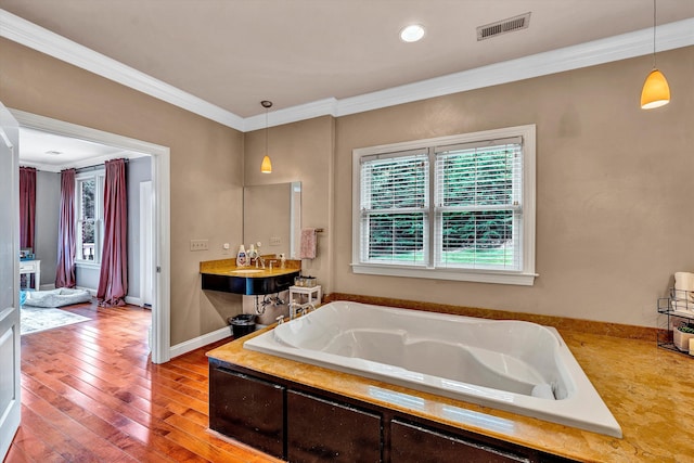 bathroom featuring wood-type flooring, a bathtub, and ornamental molding