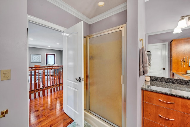 bathroom with wood-type flooring, vanity, a shower with door, and crown molding