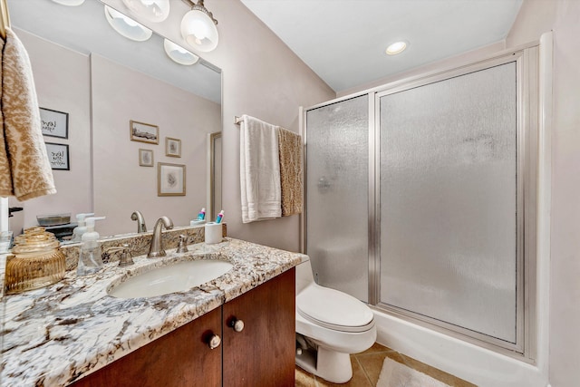 bathroom with tile patterned floors, vanity, a shower with shower door, and toilet