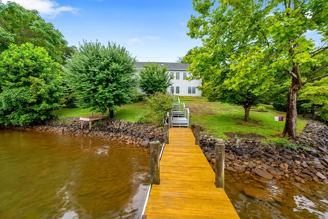 view of dock featuring a lawn and a water view