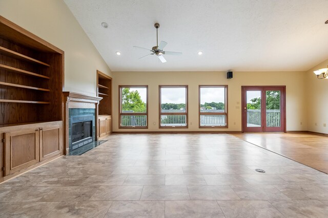 unfurnished living room featuring ceiling fan, built in shelves, vaulted ceiling, light tile patterned floors, and a fireplace