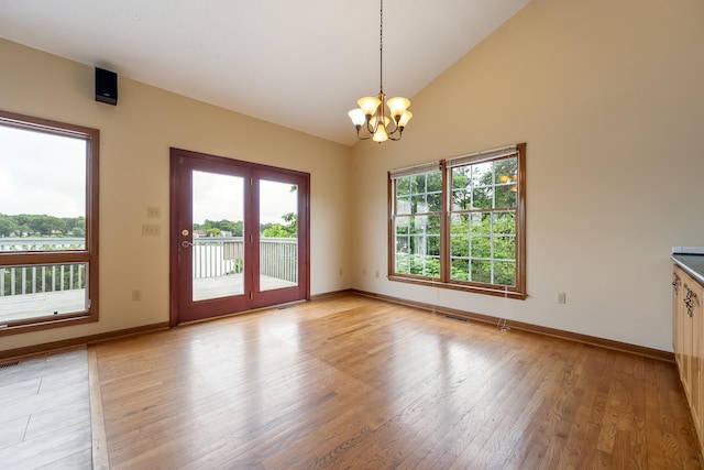 unfurnished room featuring light hardwood / wood-style flooring, high vaulted ceiling, and a chandelier