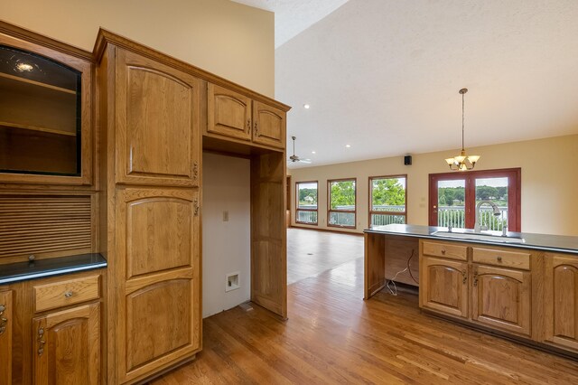 kitchen featuring light wood-type flooring, sink, an inviting chandelier, and pendant lighting