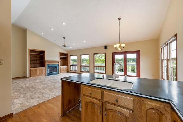 kitchen featuring built in shelves, light hardwood / wood-style flooring, pendant lighting, ceiling fan with notable chandelier, and sink