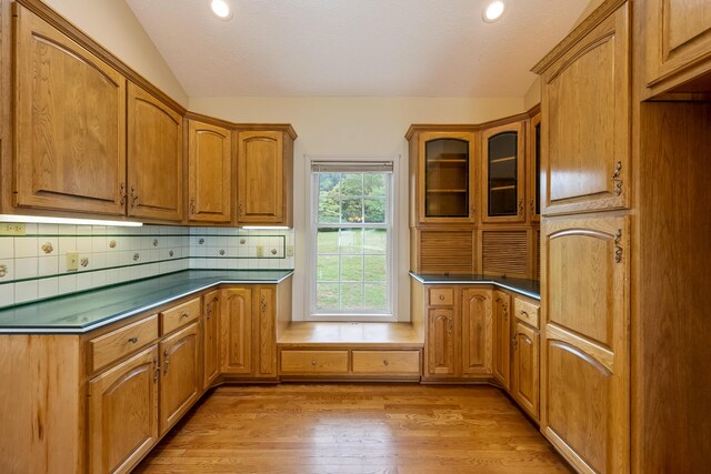 kitchen with light hardwood / wood-style floors, backsplash, and lofted ceiling