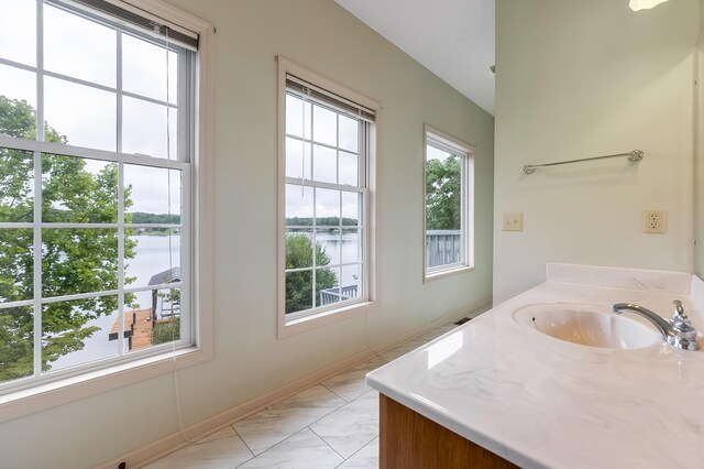 bathroom featuring a wealth of natural light, tile patterned floors, vanity, and a water view