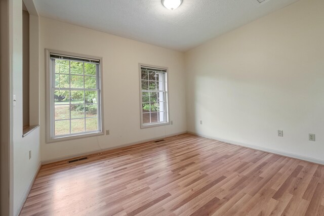 spare room featuring light wood-type flooring and a textured ceiling