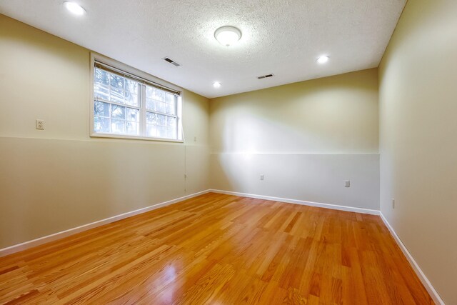 empty room with a textured ceiling and light hardwood / wood-style floors