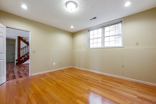 unfurnished room with a textured ceiling and light wood-type flooring