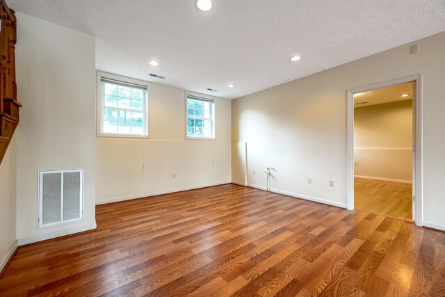 unfurnished room with a textured ceiling and hardwood / wood-style flooring