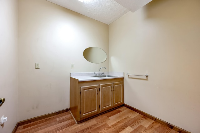 bathroom with a textured ceiling, vanity, and wood-type flooring