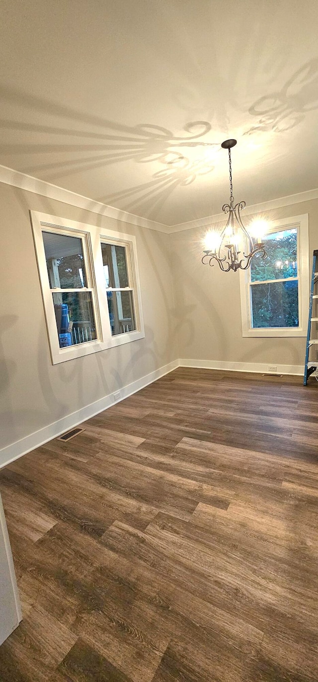 unfurnished dining area with crown molding, wood-type flooring, and an inviting chandelier