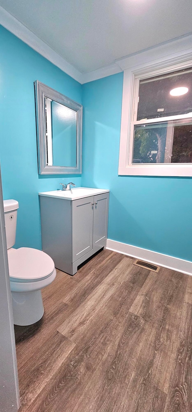 bathroom with hardwood / wood-style floors, toilet, vanity, and ornamental molding