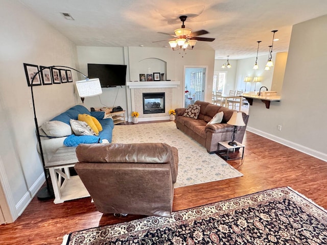 living room featuring ceiling fan, a tile fireplace, and wood-type flooring