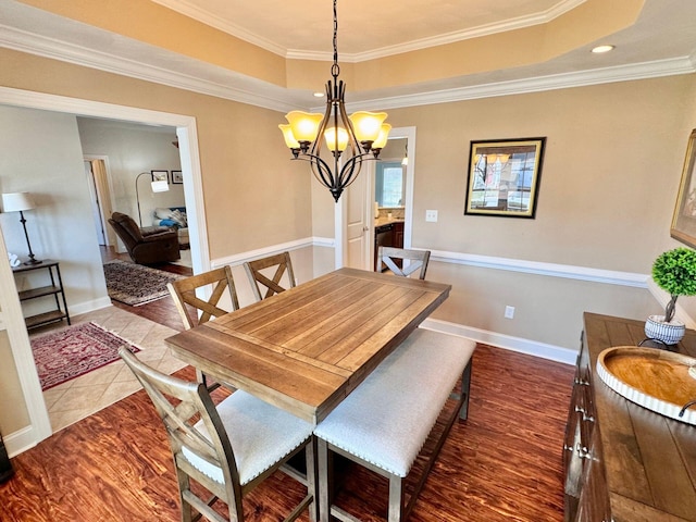 dining area with a tray ceiling, crown molding, a chandelier, and hardwood / wood-style flooring