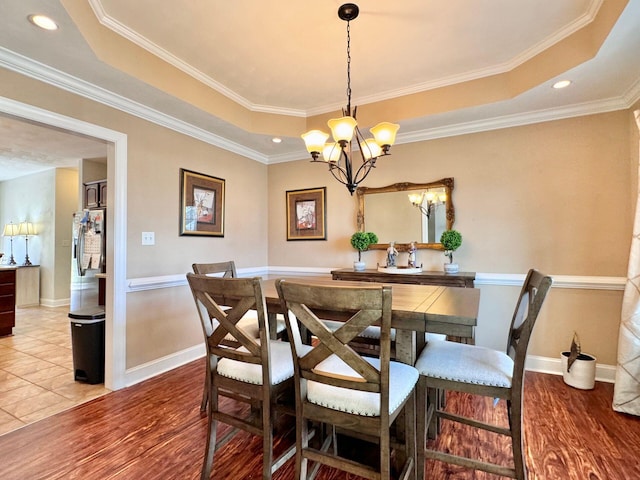 dining space featuring a notable chandelier, light hardwood / wood-style flooring, a tray ceiling, and ornamental molding