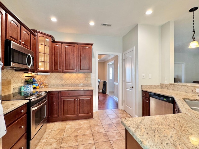 kitchen with light wood-type flooring, tasteful backsplash, hanging light fixtures, appliances with stainless steel finishes, and light stone countertops