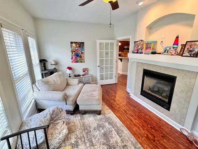 living room featuring hardwood / wood-style flooring, a tile fireplace, and ceiling fan