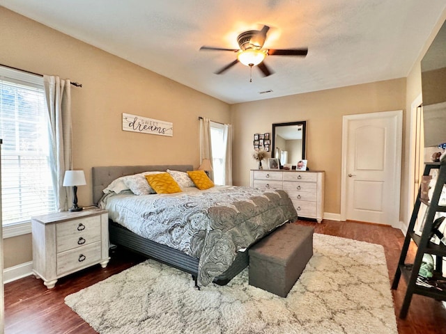 bedroom with ceiling fan, multiple windows, and dark wood-type flooring