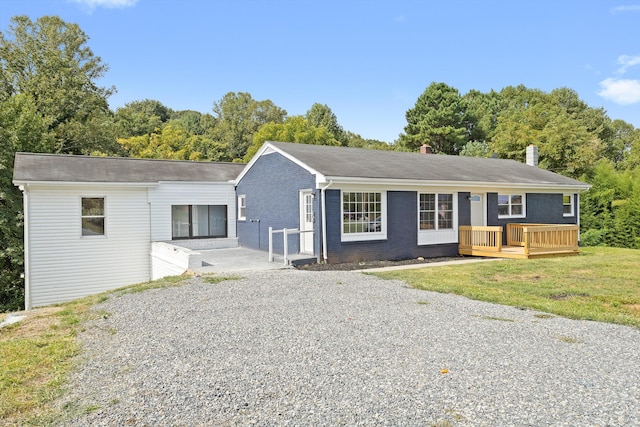 ranch-style house featuring a front yard and a wooden deck