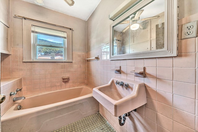 bathroom with ceiling fan, tile patterned flooring, a bathing tub, tile walls, and sink