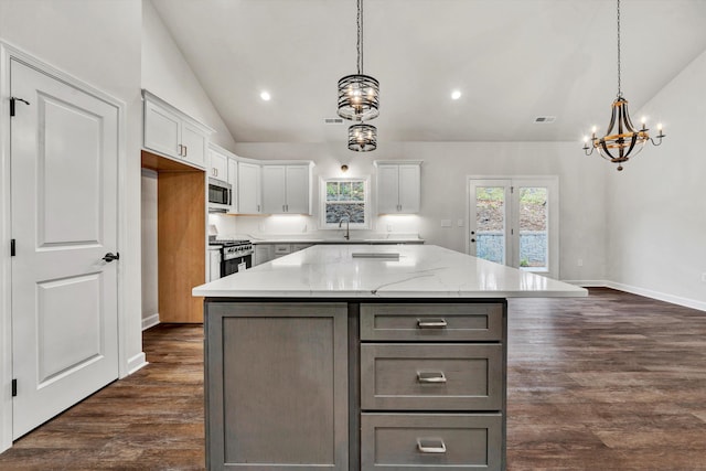 kitchen featuring hanging light fixtures, white cabinetry, vaulted ceiling, and stainless steel appliances