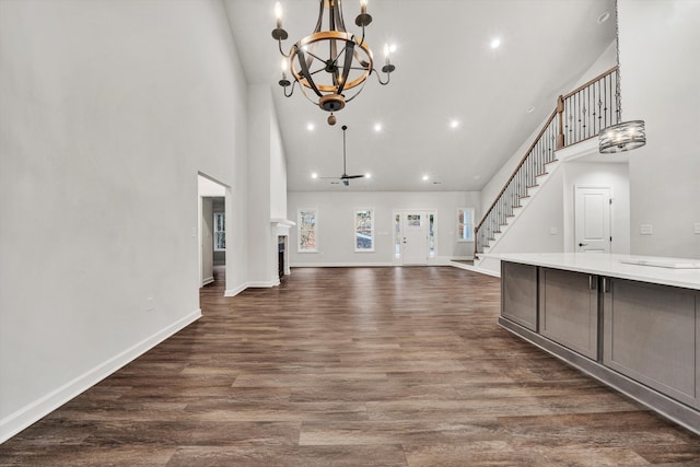 unfurnished living room featuring a chandelier, high vaulted ceiling, and dark wood-type flooring