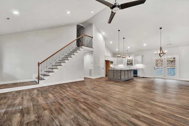 unfurnished living room with ceiling fan with notable chandelier, dark hardwood / wood-style floors, and high vaulted ceiling