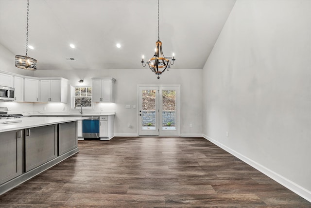 kitchen with stainless steel appliances, hanging light fixtures, dark hardwood / wood-style floors, vaulted ceiling, and white cabinets