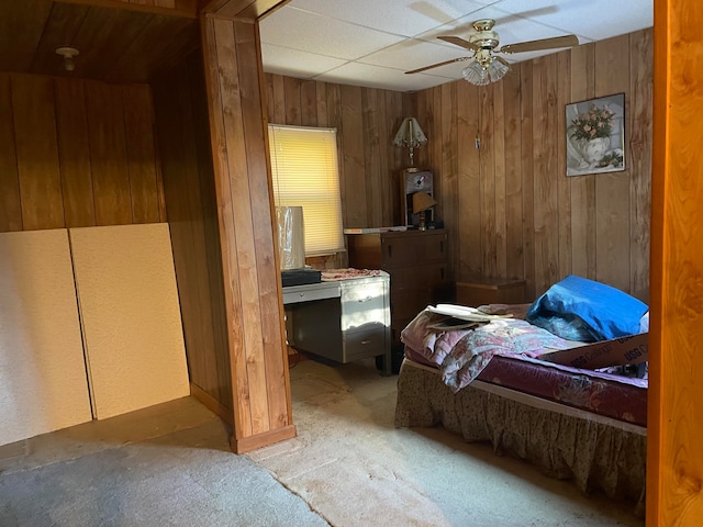 bedroom with ceiling fan and wood walls