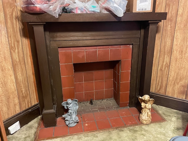 details featuring a tiled fireplace and wood walls