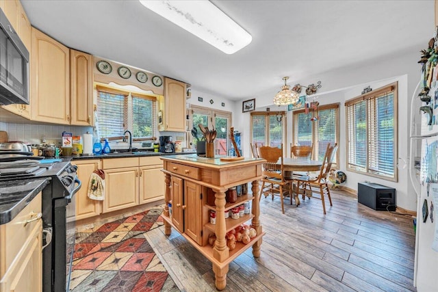 kitchen featuring dark countertops, black range with electric cooktop, light wood-type flooring, and a sink