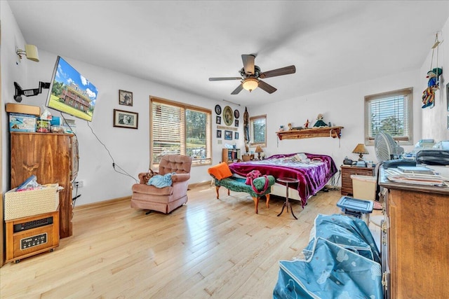 bedroom with baseboards, multiple windows, a ceiling fan, and light wood finished floors