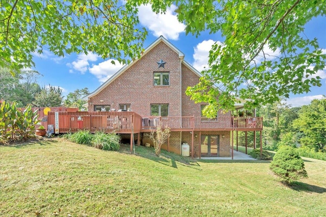 rear view of property featuring a wooden deck and a lawn