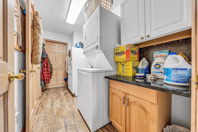 laundry area featuring cabinet space, light wood-style flooring, and stacked washing maching and dryer