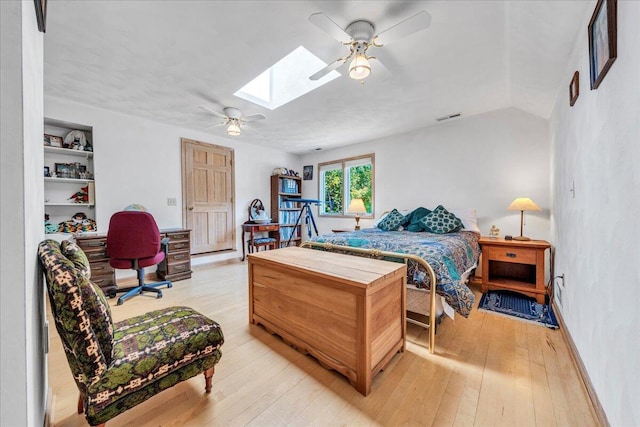 bedroom featuring visible vents, a ceiling fan, vaulted ceiling with skylight, light wood finished floors, and baseboards